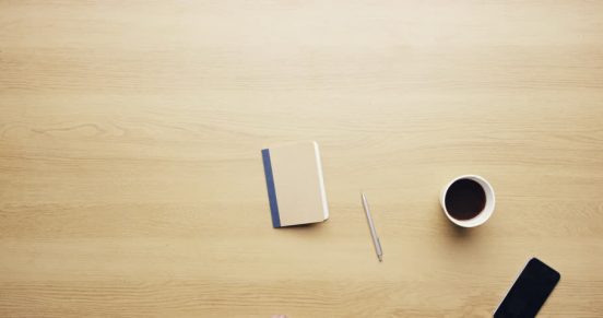 Desk top with notebook, cup of coffee, a pencil and a mobile phone